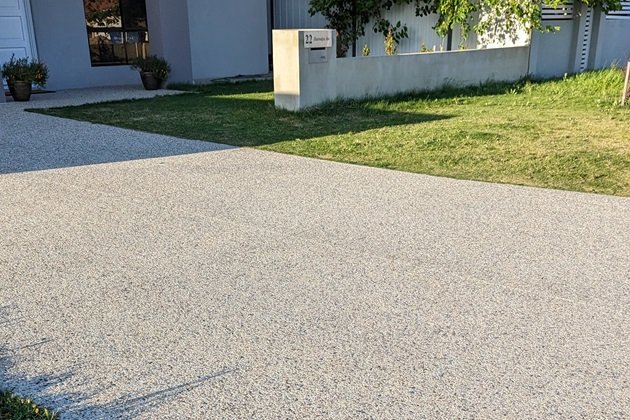 Garden pathway made of exposed aggregate concrete, bordered by lush landscaping